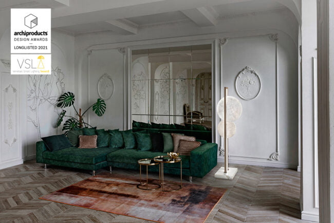 Modern living room with a green sectional sofa, decorative rug, and wall art.
