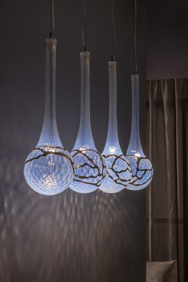 Modern pendant light fixture with glass shades in a dimly lit room.