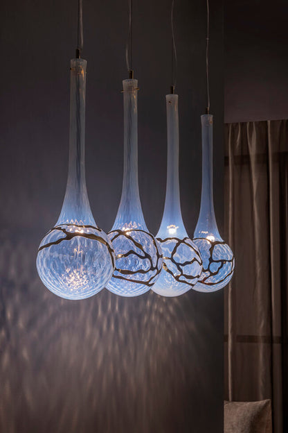 Modern pendant light fixture with glass shades in a dimly lit room.