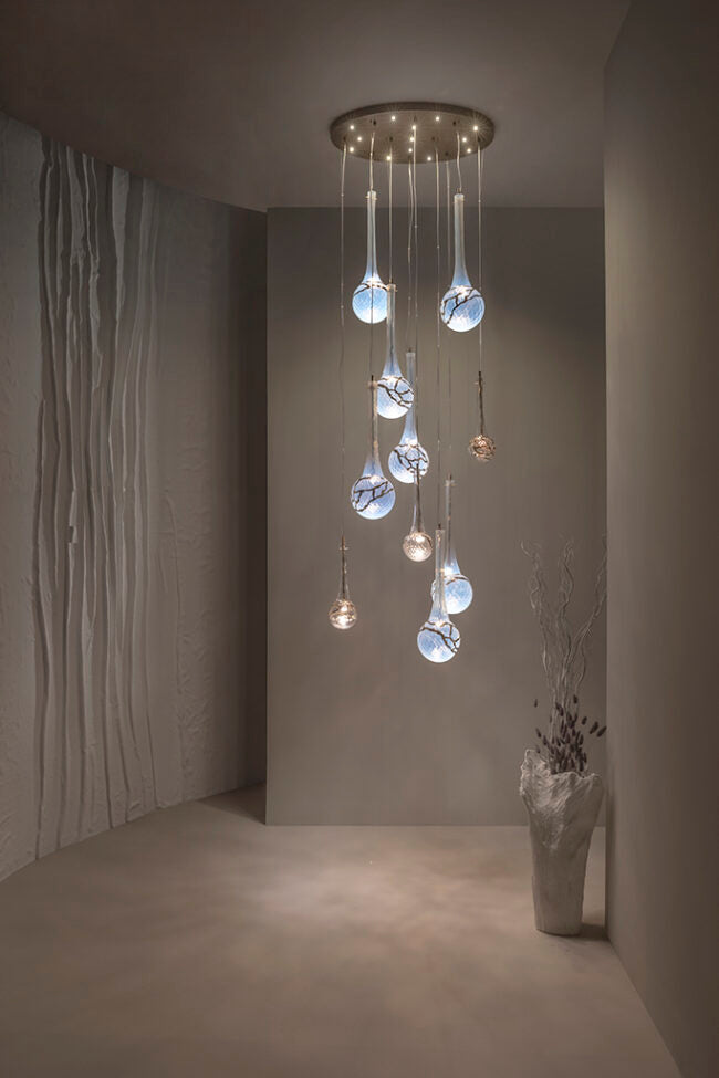Modern chandelier with glass shades in a dimly lit room.
