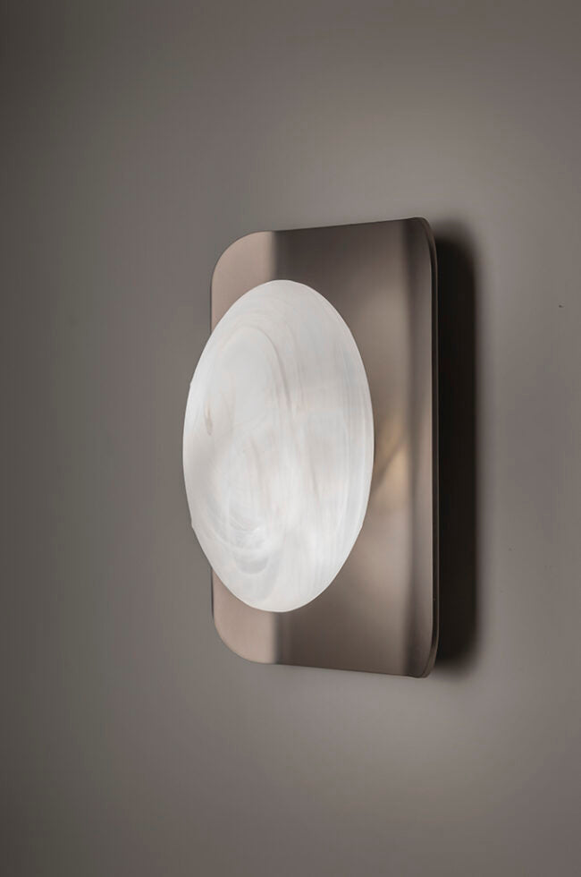 Wall-mounted light fixture with a circular glass shade on a gray background