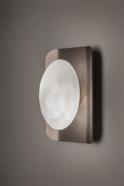 Wall-mounted light fixture with a circular glass shade on a gray background