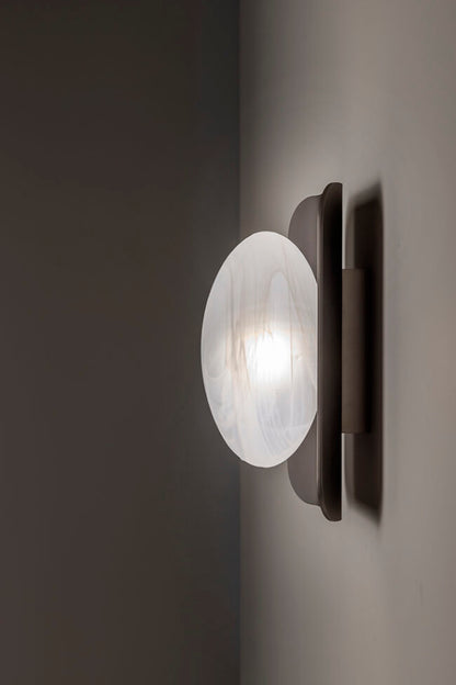 Wall-mounted light fixture with a glass shade on a dark background