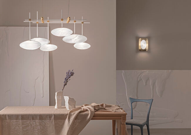 Modern dining room with a chandelier and wall light fixture.