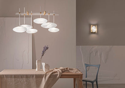 Modern dining room with a chandelier and wall light fixture.