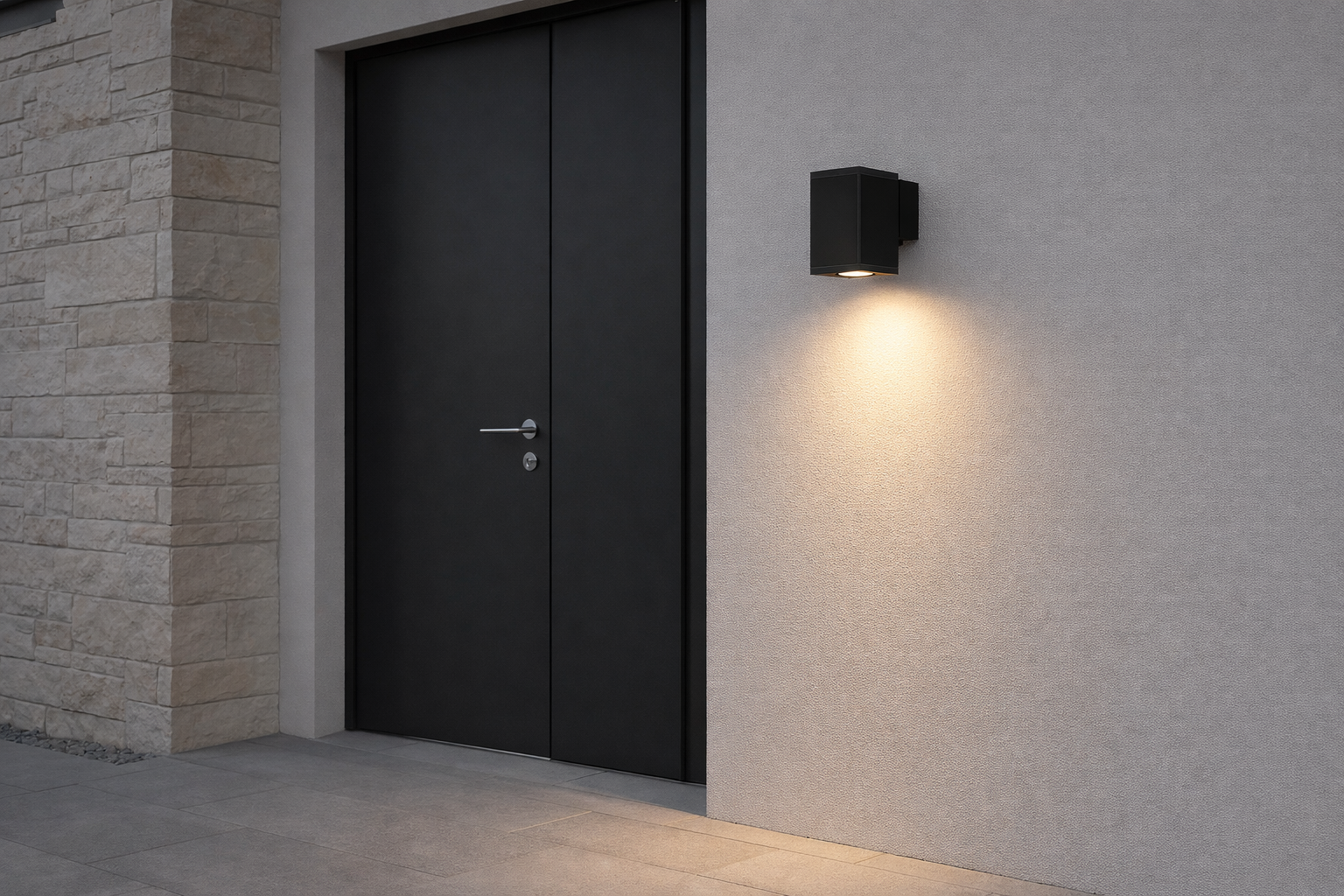 Modern black door with wall-mounted light fixture on a gray wall.