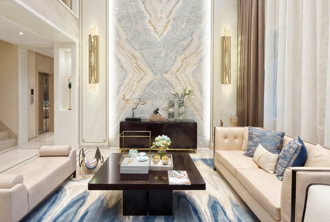 Modern living room with marble wall, beige sofa, and decorative elements.