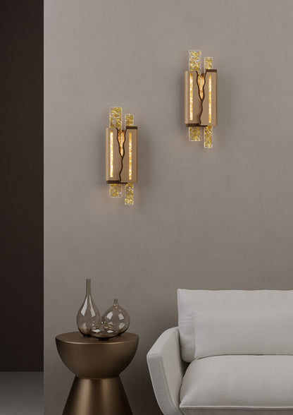 Two gold wall sconces on a gray wall with a side table and sofa in the foreground.