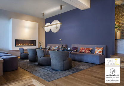 Modern living room with gray sofa, chairs, and decorative pillows against a blue wall.