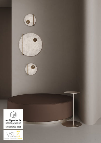 Decorative wall art pieces on a gray wall with a brown round seat and small table.