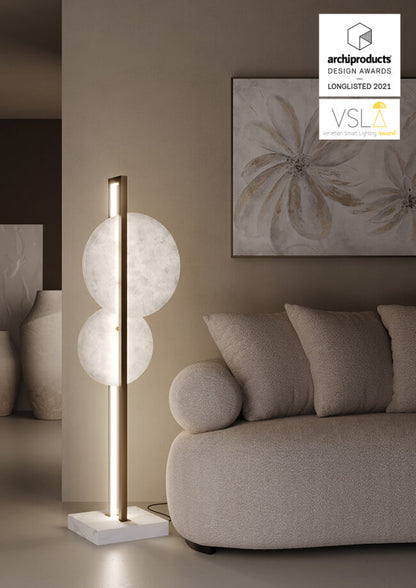 Modern floor lamp in a living room setting with a sofa and decorative painting.