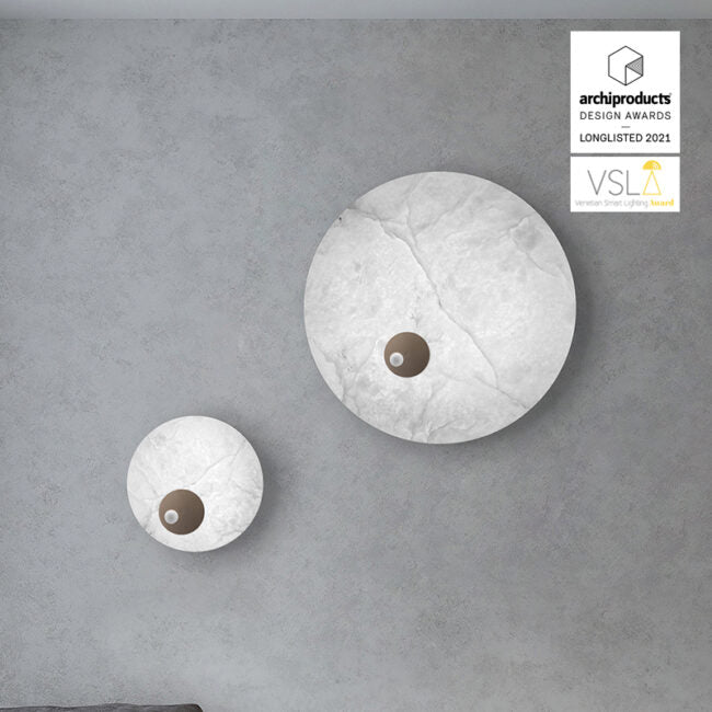 Two round wall lights on a gray wall with design awards logo.