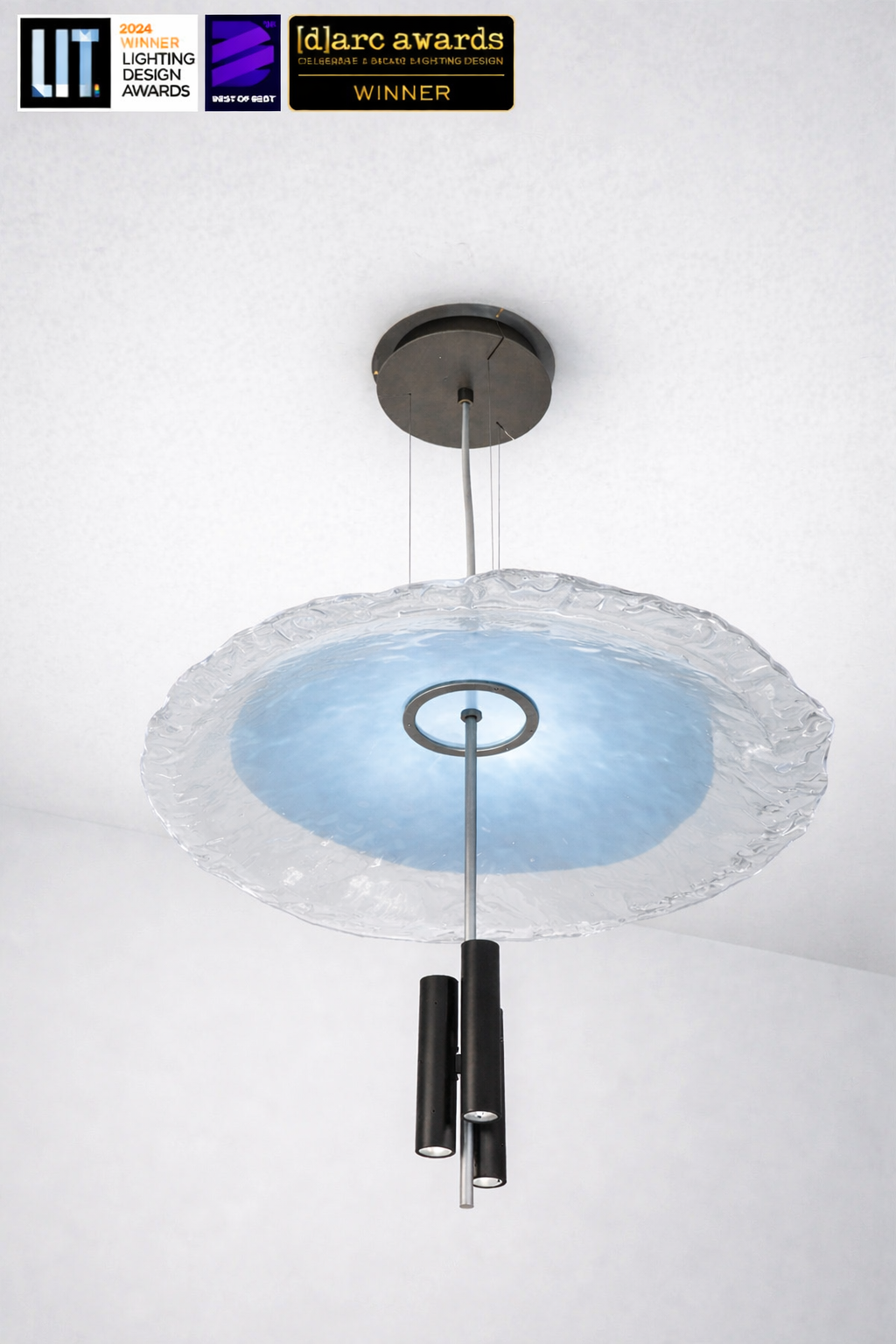 Modern pendant light with a blue glass shade on a white ceiling, featuring awards at the top.